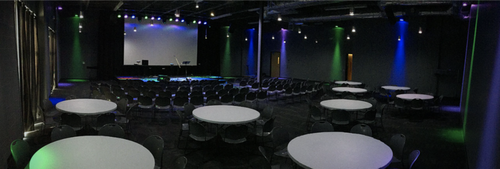 Reception tables and chairs with large presentation screen at the front of the room.